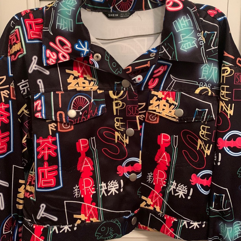 This is a black jean jacket with colorful graphic detail.